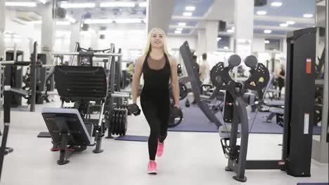 Young-attractive-female-bodybuilder-performs-squats-with-dumbbells-in-her-hands.-Fitness-and-workout.-Healthcare
