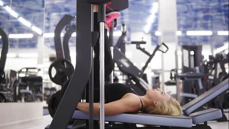 Attractive-young-blond-caucasian-woman-with-sporty-body-smiling-while-exercising-on-leg-press-mashine-at-the-gym.-Healthy-lifestyle-concept.