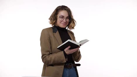 Smiling-beautiful-brunette-young-woman-in-glasses-and-brown-jacket-isolated-over-white-background-in-studio.-People-sincere-emotions,-lifestyle-concept.-Reading-book,-excited-and-thoughtfully-smiling