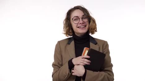 Smiling-millennial-woman-student-holding-books-and-looking-to-the-camera-on-white-background.-Young-european-female-in-stylish-glasses-studying-at-university-or-fresh-employee