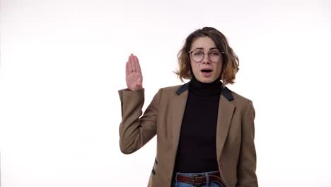 Annoyed-pretty-woman-standing-in-front-the-camera-isolated-on-a-white-background-and-showing-blahblah-gesture,-gossips.-Irritated,-emotional.-Wearing-brown,-retro-jacket,-jeans-and-stylish-glasses