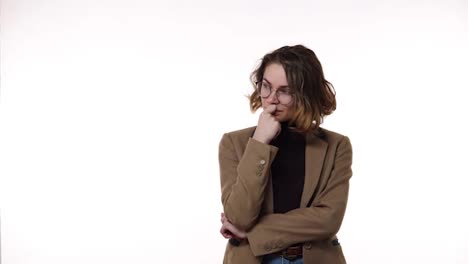 Young-pretty-woman-in-stylish-glasses-and-brown-jacket-looks-confused-and-thoughtful-then-gets-an-idea.-Beautiful-young-woman-gets-excited-after-remembering-something,-pointing-up-with-a-finger