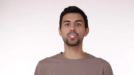 Attractive-young-bristled-man-blowing-chewing-gum-bubble-with-eyes-wide-open-isolated-over-white-background.-Chewing-gum-bursts-on-the-chin.-Slow-motion