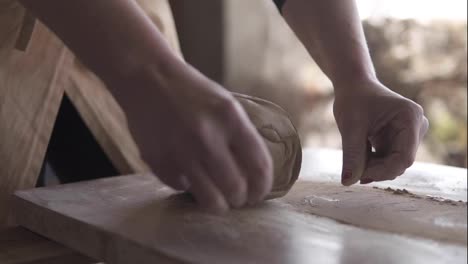 Unrecognizable-woman-cutting-the-clay-before-begin-sculpting-close-up-in-workshop.-Making-ceramic-products.-Artistic-creative.-Sculptor-sculpts-pots-products.-Master-crock.-Potter's-work-close-up