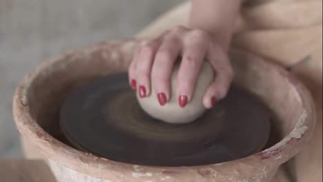 A-close-up-of-hands-working-on-a-ceramic-piece-on-a-pottery-wheel-in-a-clay-studio.-The-artist-uses-her-hands-to-shape-the-clay.-Slow-motion