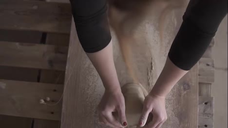 Top-footage-of-female-hands-with-beautiful-red-manicure-holding-clay-and-hardly-kneading-it-on-a-worktop.-Woman-wearing-beautiful-red-manicure