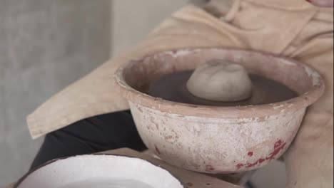Female-artist-potter-in-the-workshop-creating-a-ceramic-product.-Woman-splashing-water-on-a-clay-piece-on-spinning-wheel.-Creative-workshop.-Slow-motion