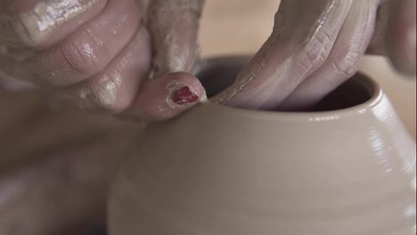 Skilled-wet-female-hands-of-potter-shaping-the-clay-on-potter-wheel-and-sculpting-vase-using-fingers.-Manufacturing-traditional-shaped-vase.-Close-up