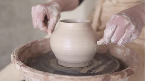 The-female-potter-cuts-the-base-of-the-vase-with-a-fishing-line-and-split-the-vase-into-two-half.-Girl-makes-pottery-from-clay-close-up.-Making-ceramic-products-from-white-clay