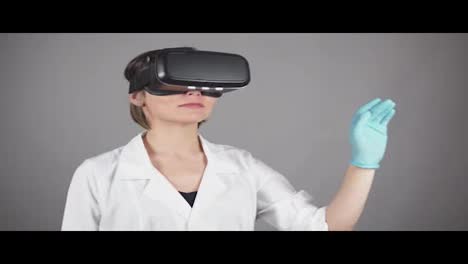 Feale-Arzt-Führt-Experimentelle-Medizinische-Eingriffe-Durch-Und-Trägt-Ein-Virtual-Reality-Headset,-Isoliert-Auf-Grauem-Hintergrund.-Modernes-Gesundheitskonzept.-In-4k-Gedreht