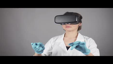 Feale-Arzt-Führt-Experimentelle-Medizinische-Eingriffe-Durch-Und-Trägt-Ein-Virtual-Reality-Headset,-Isoliert-Auf-Grauem-Hintergrund.-Modernes-Gesundheitskonzept.-In-4k-Gedreht