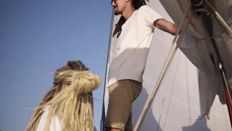 Healthy-outdoor-lifestyle-sailing-luxury-yacht-with-young-stylish-couple-enjoying-relaxation-and-freedom.-Caucasian-young-couple-with-dreadlocks.-Low-angle-view