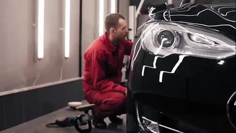 Autocenter-worker-doing-the-final-wiping-of-perfectly-polished-new-black-car.