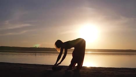 Junge-Frau-Macht-Yoga-Übungen-–-öffnet-Ihre-Yogamatte-In-Der-Nähe-Von-Meer-Oder-Ozean.-Sonnenuntergang-Oder-Sonnenaufgang.-Gesundheitskonzept.-Zeitlupe.