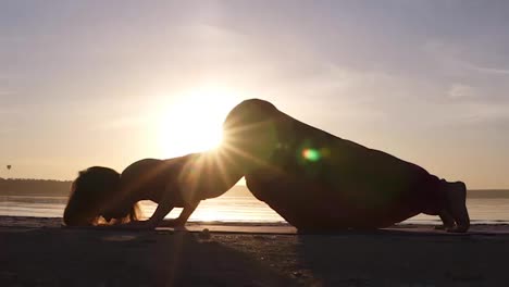 A-silhouette-footage-of-a-woman-who-is-doing-Urdhva-Mukha-Shvansana-on-the-beach.-Backbend.-Sun-shines-on-the-background