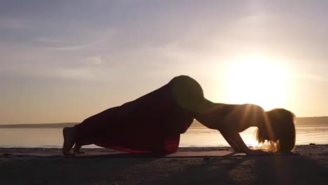 Beautiful-footage-on-sunset-beach,-woman-doing-yoga-asana-on-a-mat,-backbend,-Urdhva-Mukha-Shvansana.-Slow-motion