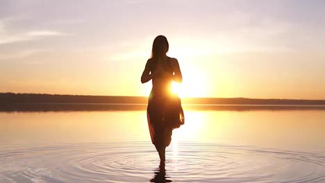 Beautiful-footage-on-sunset-beach,-woman-doing-yoga-asana-Utthita-Hasta-Padagushthasana-staying-in-the-water.-Slow-motion