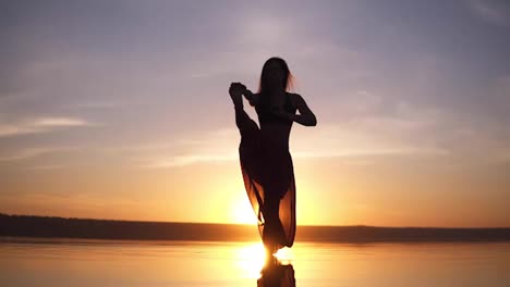 Silhouette-Yoga-Frau-Praktiziert-Yoga-Haltung-An-Der-Küste-Bei-Wunderschönem-Sonnenuntergang.-Atemberaubender-Blick-Auf-Eine-Frau-In-Yogi-Hosen.-Vorderansicht