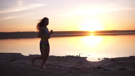 Beauty-runner-woman-running-over-sunset.-Young-woman-jogging-along-the-sea-coast.-Healthy-lifestyle-concept.-Slow-motion