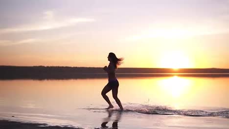 Slender-woman-with-long-hair-running-outdoors.-Jogging-by-the-water.-Seaside.-Sun-shines-on-the-background