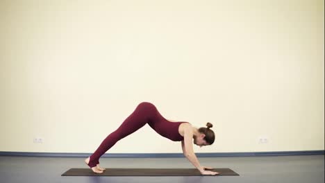 Young-attractive-woman-in-one-piece-sports-wear-doing-downward-dog-yoga-asana-to-keep-her-body-fit-and-flexible.