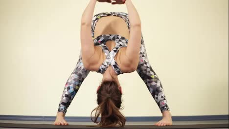 Young-flexible-woman-doing-downward-body-twists-while-practising-yoga.