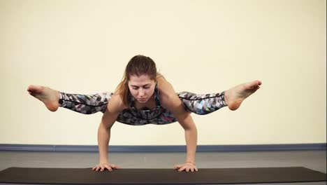 Young-attractive-woman-trying-to-achieve-balance-when-entering-one-of-yoga-asanas-and-placing-the-weight-of-entire-body-on-her-arms.