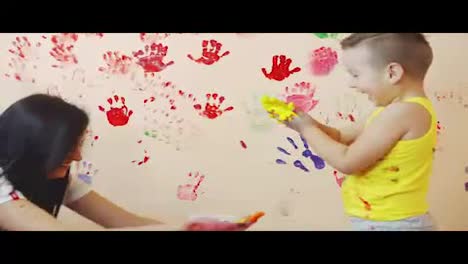 Happy-mother-and-her-cute-boy-having-fun-together-leaving-their-colorful-handprints-on-the-wall.-Young-happy-family.-Mother-and-child-concept