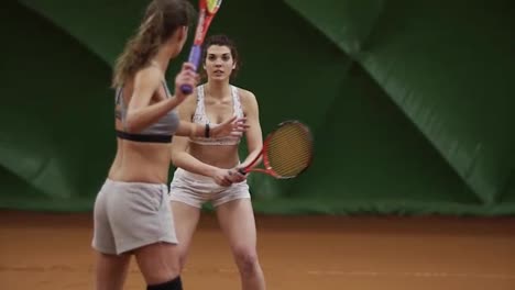 The-female-tennis-coach-shows-the-technique-of-rack-with-racket-to-a-beautiful-long-haired-girl-on-the-tennis-court.-Slow-motion