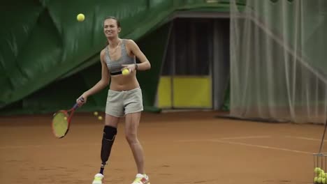 A-tall,-smiling-girl-with-a-handicap-serving-balls-in-tennis.-Cheerful-and-active.-Indoors-tennis-court