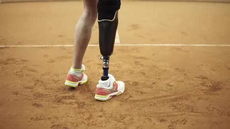 Footage-from-the-bottom-up-of-a-sports,-long-haired-woman-with-a-physical-disability-playing-tennis.-Close-up