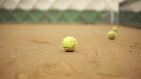 Closeup-footage-of-female-legs-in-sports-sneakers-and-prosthesis-on-her-leg-picking-up-tennis-balls-from-the-tennis-court-ground