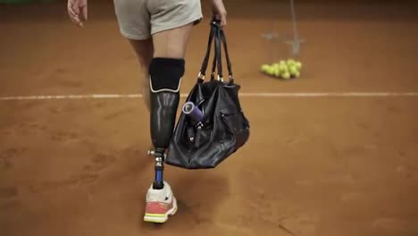 Smiling-girl-athlete-comes-to-tennis-training,-pulls-out-a-racket-and-goes-to-the-court.-Leg-prosthesis.-Slow-motion