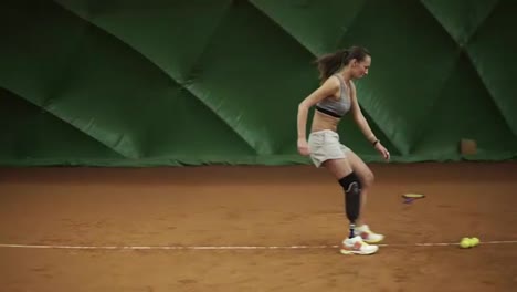 Athlete-on-the-leg-prosthesis-runs-around-the-court-setting-tennis-balls-in-the-corners.-Trainings.-Sportswear.-Indoors