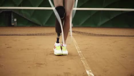 Close-up-footage-of-a-slender-girl-with-a-right-leg-prosthesis-jumping-rope-on-a-tennis-court-in-sneakers.-Indoors