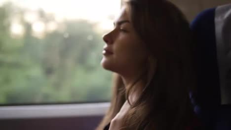 Pensive-woman-relaxing-and-looking-out-of-a-train-window.-Side-view.-Travel,-transport-concept