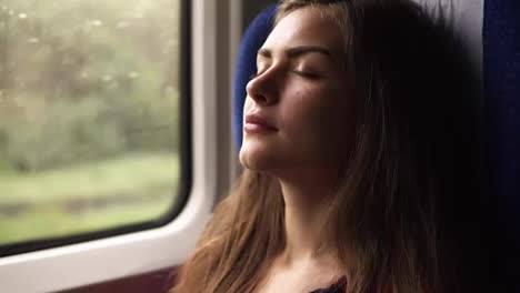 Aim-footage-of-a-gorgeous-young-woman-travelling-by-train.-Have-a-nap.-Closed-eyes.-Sitting-near-the-window.-Long-haired-brunette