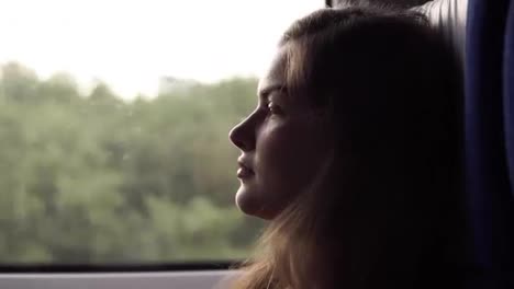 Side-view-of-a-relaxed,-long-haired-beautiful-girl-riding-on-the-speed-train.-Profile.-Sitting-near-the-window.-Thoughtful,-calm-woman