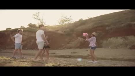 Joyful-young-friends-playing-volley-ball-on-the-beach-by-the-sea-during-the-sunset.-Teambuilding.-Shot-in-4k