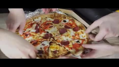 Close-up-Of-People-Hands-Taking-Slices-Pizza-from-food-delivery-open-box.-Tasty-Service-to-office.-Focus-changes-on-hands.-Shot-in-4k