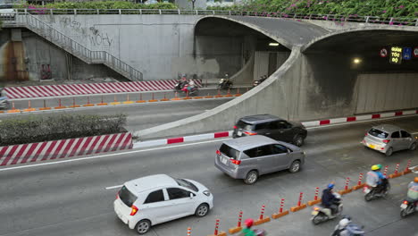 A-busy-highway-tunnel-with-vehicles-and-motorbikes-driving-in-and-out-on-different-lanes-in-Saigon,-Vietnam