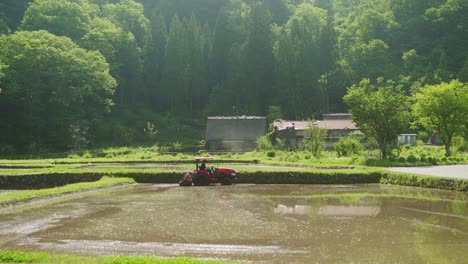 Farmer-Ploughing-Partial-Flooded-Rice-Field-With-Tractor-In-In-Shirakawago-Countryside