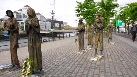 Famine-Commemorative-Monument-in-Dublin-while-a-local-pass-by,-Ireland