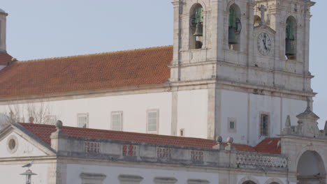 Die-Kirche-Hinter-Einer-Tanzenden-Frau-An-Einem-Süßigkeitenstand-In-Nazare,-Portugal