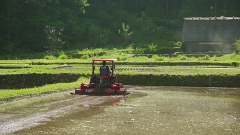Farmer-Ploughing-Partial-Flooded-Rice-Field-With-Red-Tractor-In-In-Shirakawago-Countryside