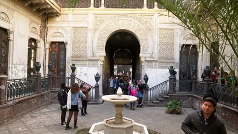 Hand-Held-Shot-Inside-La-Alhambra-Palace-Moorish-Architecture-in-Santiago,-Chile-Citadel-Fountain-Landmark-with-Tourists