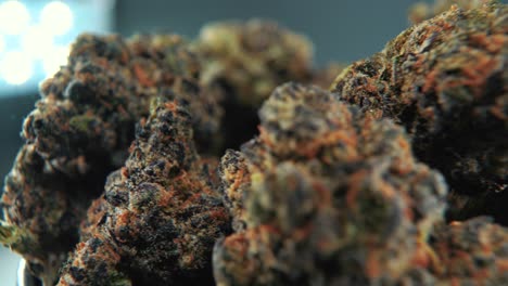 A-macro-cinematic-detailed-shot-of-a-cannabis-plant,-orange-hybrid-strains,-Indica-and-sativa-,-purple-marijuana-flower,-on-a-rotating-stand,-slow-motion,-4K,-professional-studio-lighting