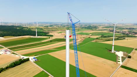 Windmill-Tower-Construction-In-Idyllic-Fields---aerial-drone-shot
