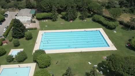 Aerial-rotational-of-an-outdoors-swimming-pool-with-swimmers-having-fun