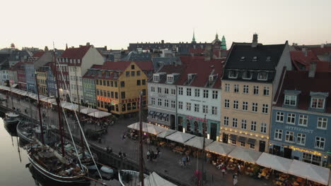 Nyhavn-In-Kopenhagen-Bei-Sonnenuntergang,-Der-Eine-Warme-Und-Einladende-Atmosphäre-Mit-Menschen-Und-Booten-Schafft,-Die-Den-Kanal-Säumen